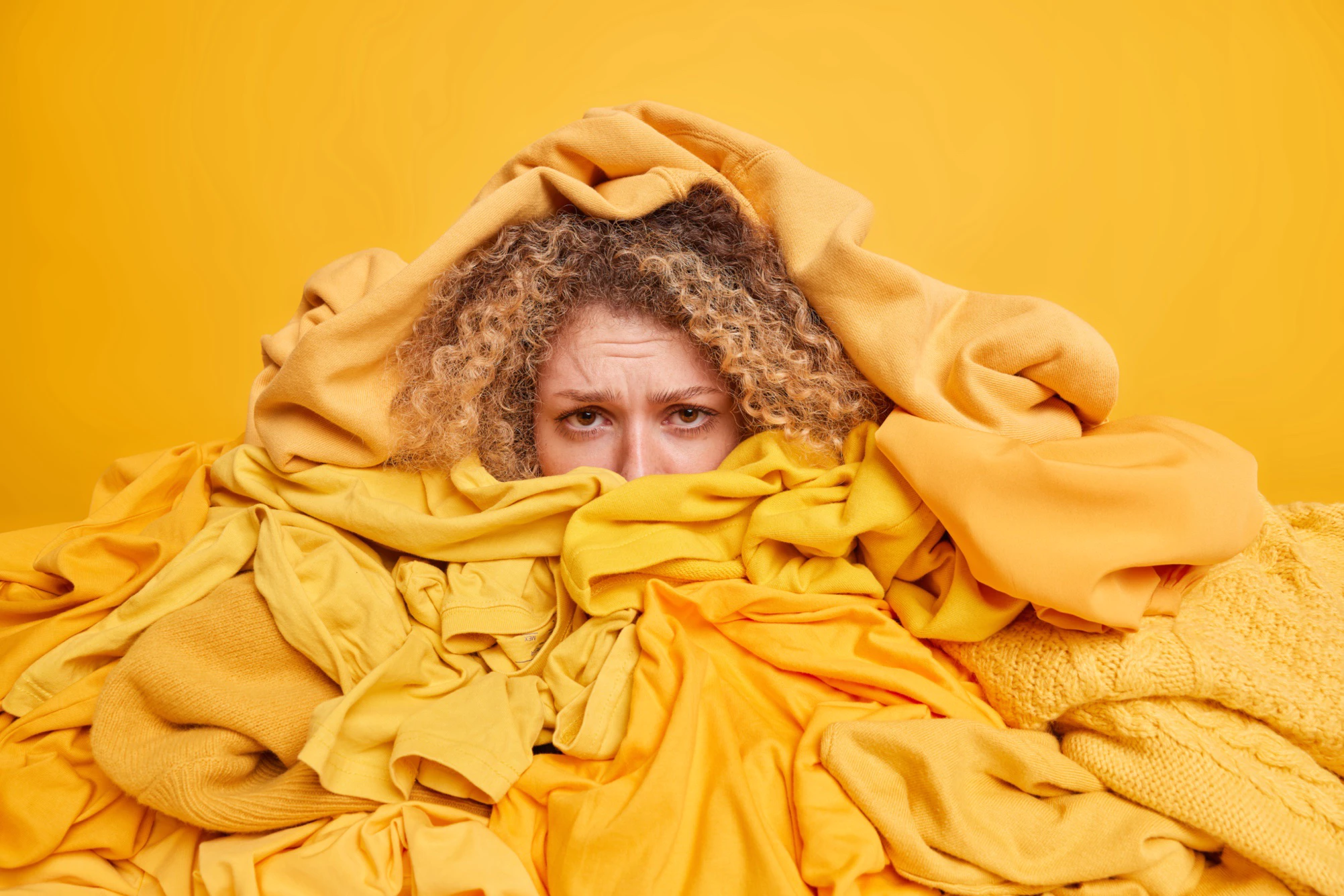 Image of woman organizing clothing - surrounded by a pile of yellow clothing