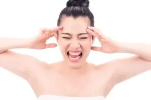 Woman holding her head in frustration, representing discomfort and stress from wearing a bra that doesn’t fit properly.
