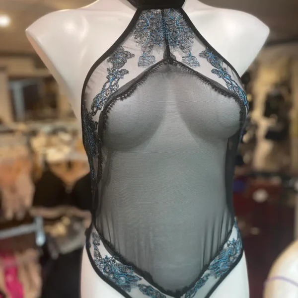 A black sheer halter-style bodysuit displayed on a mannequin, featuring intricate blue floral lace accents along the neckline and hips. The bodysuit has a high neckline with a velvet choker collar, creating an elegant and dramatic look.